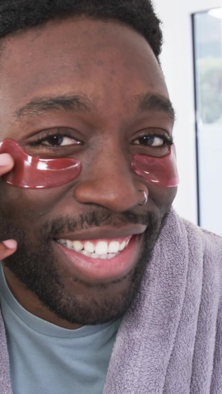 Video verticale: Individuando macchie rosse, un uomo che solleva e stende il gel sotto gli occhi sorridendo allo specchio