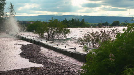 waves crashing against a bulwark and splashing up onto a pathway in slow motion