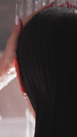 woman washes hair in shower jets closeup. lady adjusts wet hair enjoying warm liquid flow in bathroom. relaxation during spa procedures at home