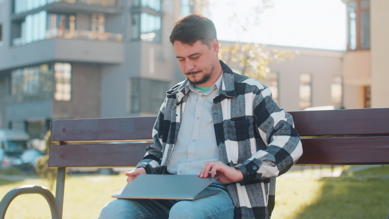 Happy mature caucasian businessman closing laptop computer while leaving downtown city street