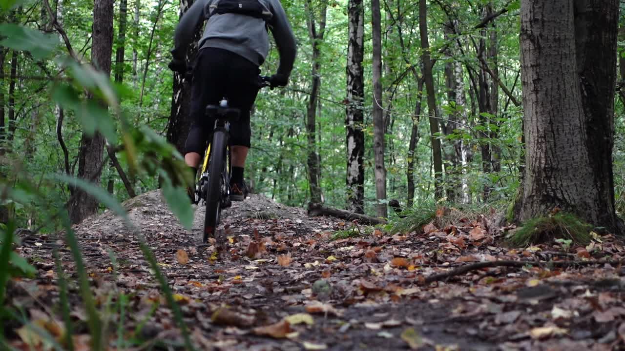 disparo estático en cámara lenta desde atrás de un ciclista de montaña saltando y cayendo en una bicicleta de montaña eléctrica en el bosque