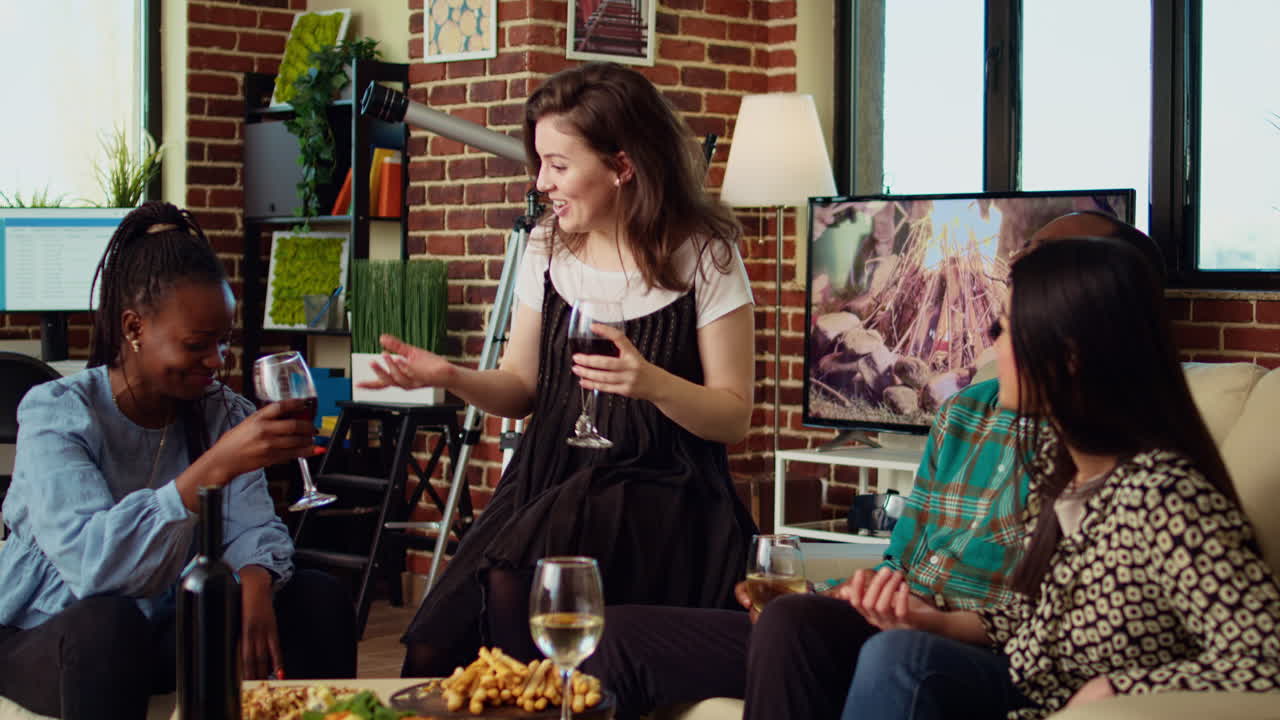Inclusive group friends celebrating woman birthday, drinking alcohol and eating appetizers in living room