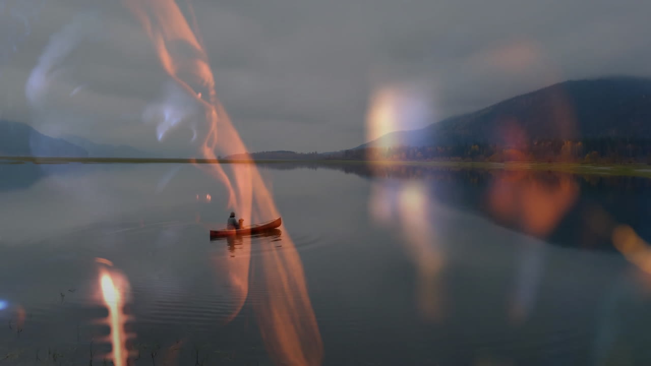 Travel scene showing man paddling red canoe on mountain lake at dusk, blending warm flame overlays