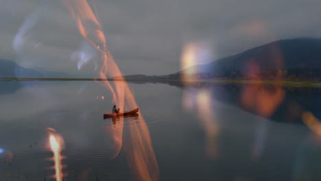 travel scene showing man paddling red canoe on mountain lake at dusk, blending warm flame overlays