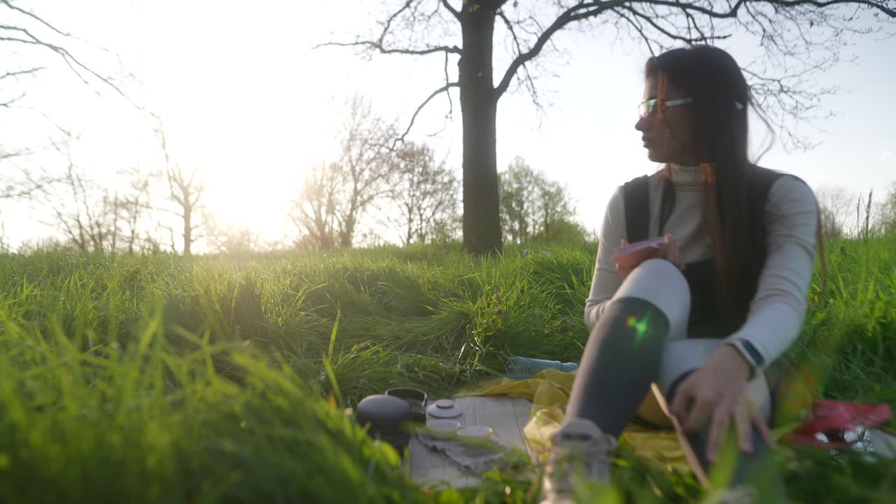 Woman enjoying a peaceful picnic in a park at sunset