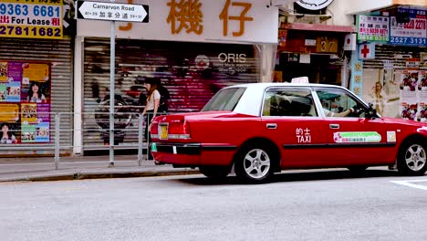 red taxi driving past busy hong kong shops