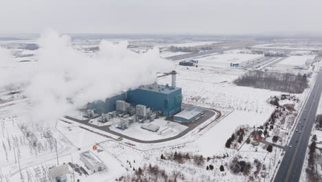una gran planta industrial que emite vapor en un paisaje nevado, temporada de invierno, durante el día, vista aérea