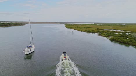 aerial view of a motorboat passing alongside a stationary sailboat, usa