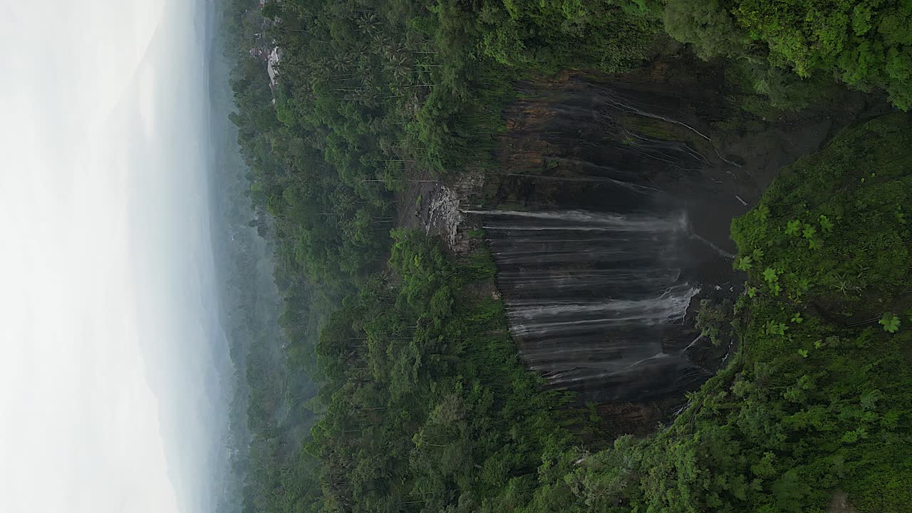 formato vertical: descenso aéreo en la impresionante cascada de java tumpak sewu