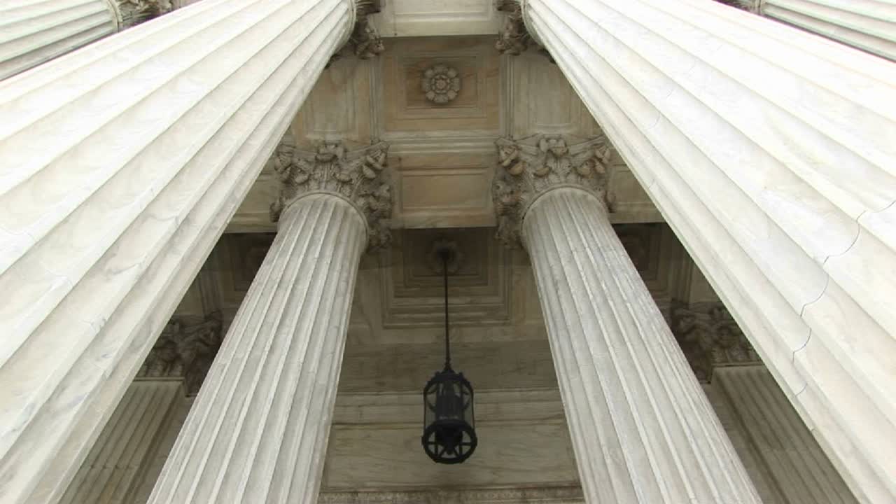 vista de columnas una lámpara colgante y puertas de bronce en la entrada oeste de la corte suprema