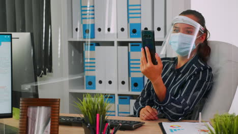mujer con máscara hablando en videocall con un compañero de trabajo remoto