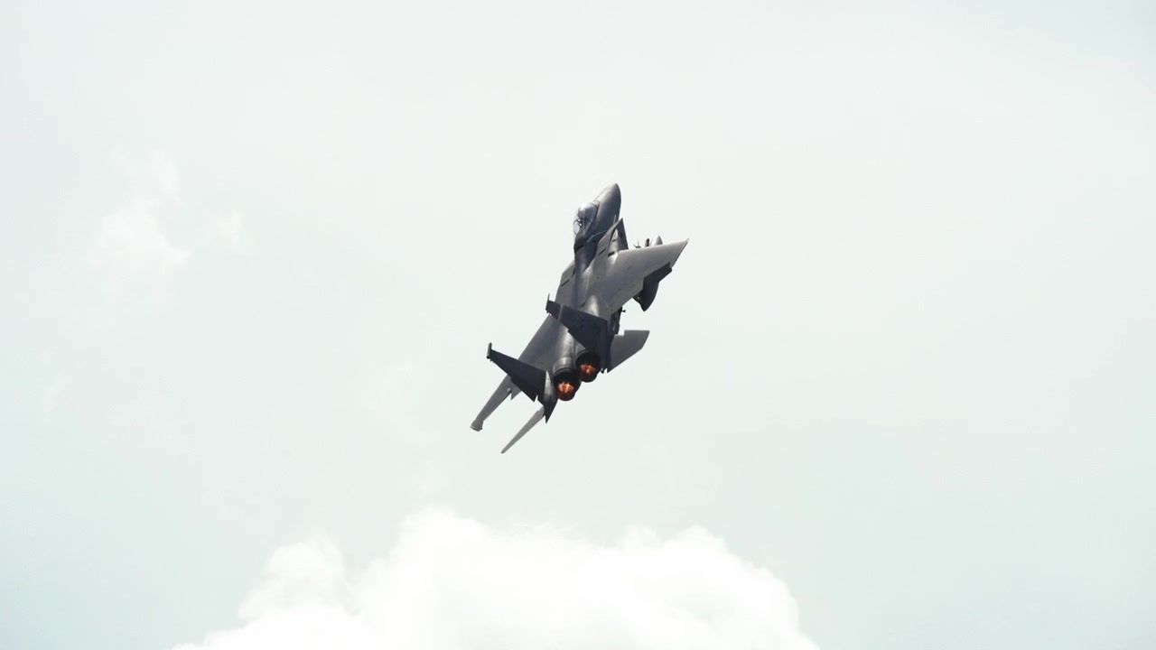 An F-15 fighter jet takes off from a runway and ascends into the sky.