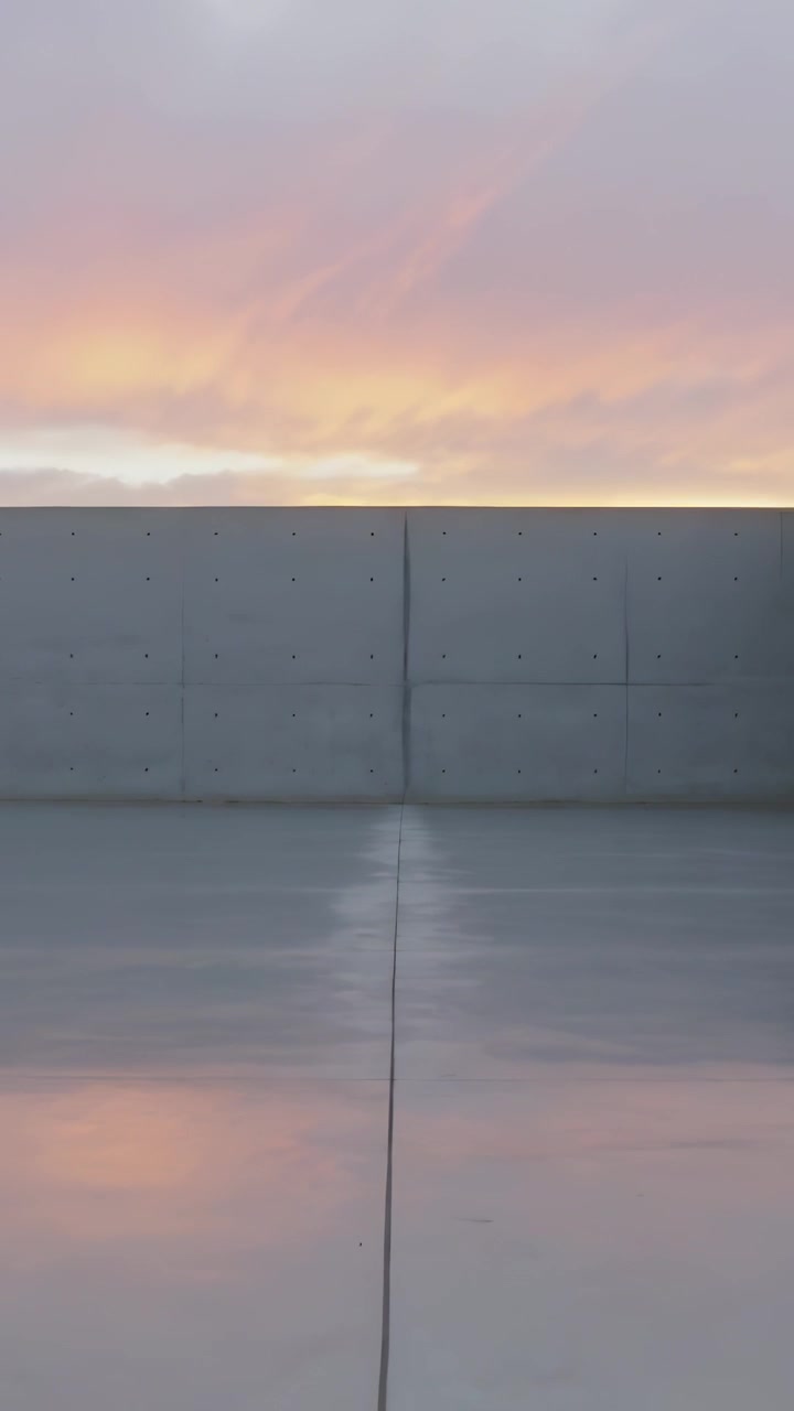 Vertical video: Showing roof concrete wall tie holes, wet floor mirroring sky, sunset shifting hues