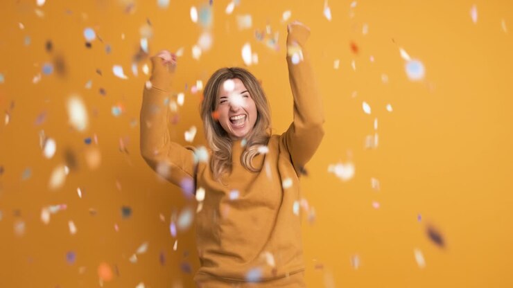 Donna eccitata con capelli biondi che esulta e festeggia un grande premio su sfondo giallo