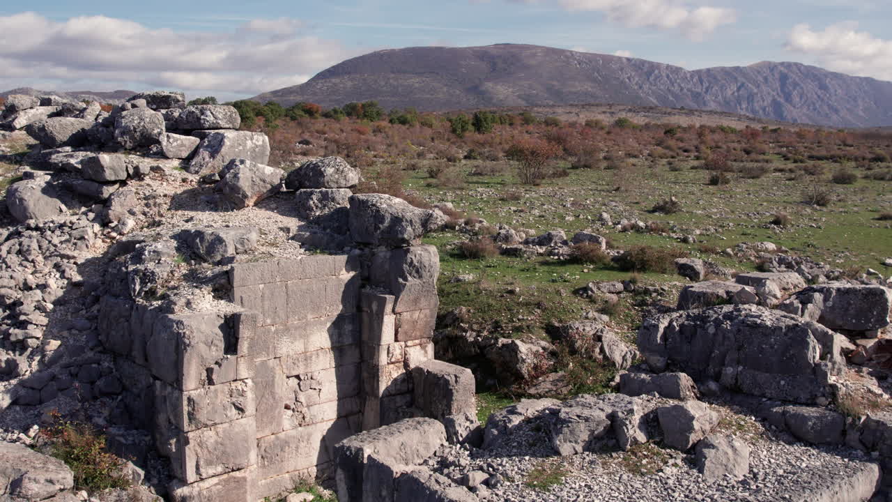 Close-up view of ancient Daorson Illyrian city ruins near Stolac, Bosnia and Herzegovina, showing massive stone blocks, collapsed walls and a wide mountain landscape under clear autumn light