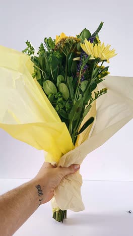 hand holding a wrapped flower bouquet