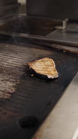 chef grabbing the grilled swordfish and putting it in the dish