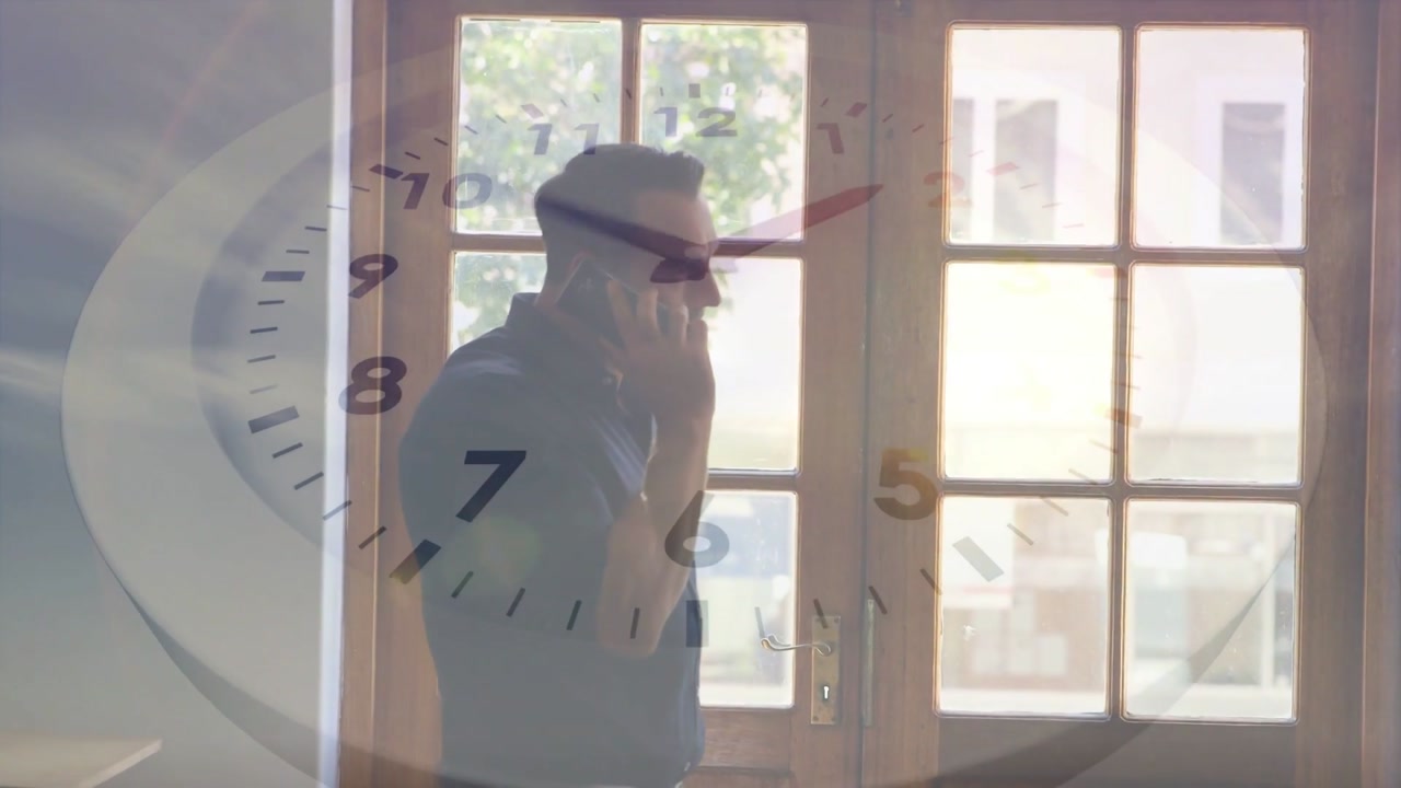 Answering mature man in collared shirt on phone at glass door, taking work call, clock moving