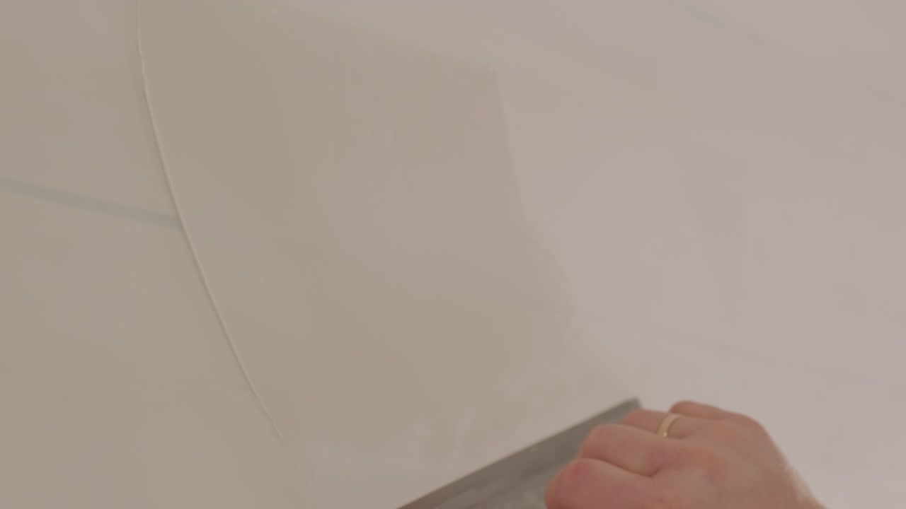 Man plastering the walls with finishing putty in room with putty spatula