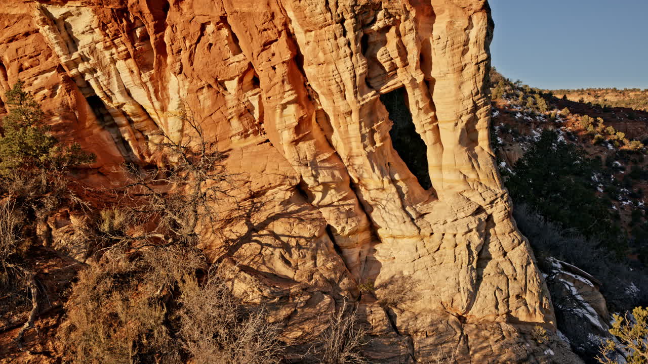 High-angle drone footage revealing a secret natural arch bathed in soft morning hues near Kanab, Utah.