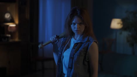 young woman with a baseball bat looking menacingly in a dim room