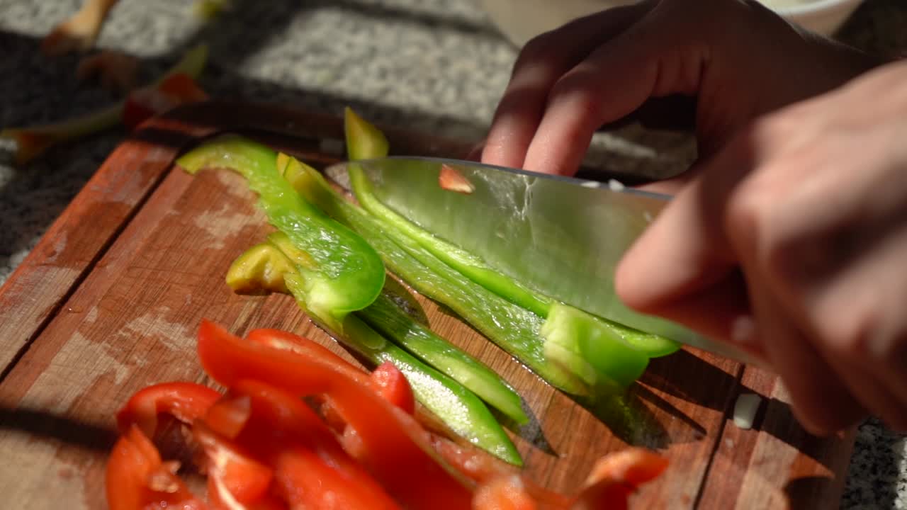 persona cortando pimientos verdes verticalmente en una tabla de cortar