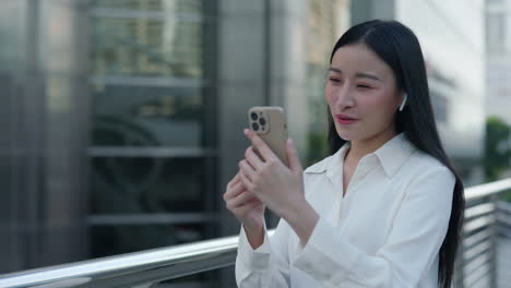 young asian woman on video call with smartphone in city