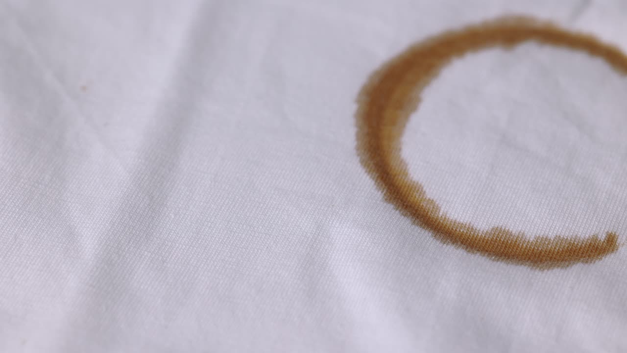A white cotton shirt stained with brown coffee stains. Must be washed thoroughly in the washing machine
