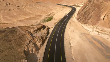 Car-zooming-by-heading-north-on-a-Desert-highway-with-cloudy-blue-sky