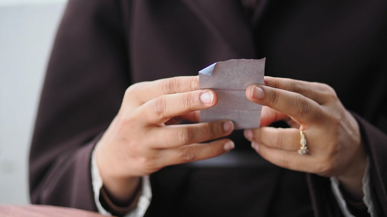 Close-up of Hand Holding a Small Folded Paper