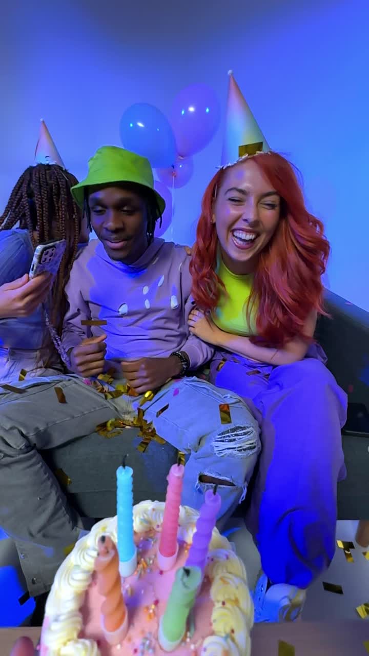 fotografía de estudio de video vertical de los amigos de la generación z celebrando el cumpleaños del hombre con pastel de fiesta y velas sentados en el sofá 3