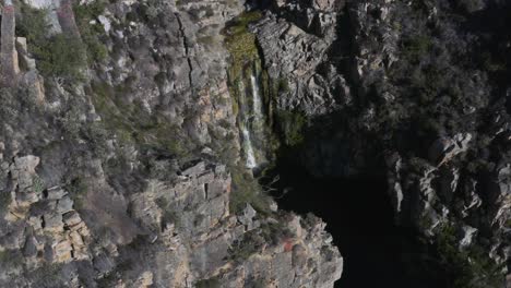 Weite-Luftaufnahme-Eines-Wasserfalls-Mit-Moos-Auf-Den-Klippen