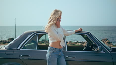 beautiful girl tourist calling standing on seashore near retro car at summer day