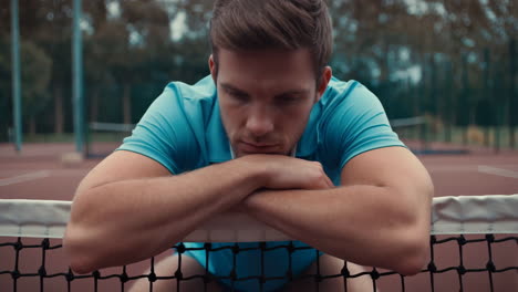 man resting on a tennis net