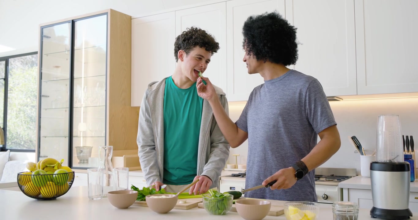 Two Young Men Preparing Fresh Salad Together in Modern Kitchen