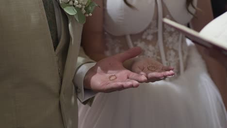 Novia-Y-Novio-Sosteniendo-Anillos-De-Boda-En-Sus-Manos-Durante-La-Ceremonia,-Simbolizando-Amor-Y-Compromiso.