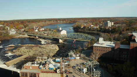 Brunswick,-Maine-Industrial-area-on-the-banks-of-a-river-crossed-by-truss-bridge,-drone