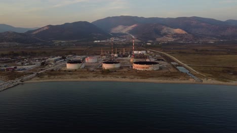 Aerial-approach-to-oil-refinery-by-the-sea-at-dusk