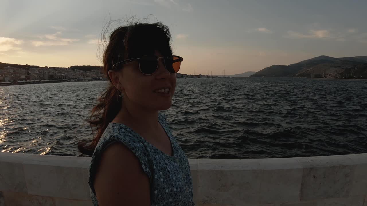 joven morena con un vestido verde caminando por un puente de piedra en argostolion, ciudad en cefalonia, grecia