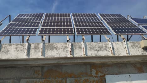 Solar-panels-lined-up-in-the-ecological-building-in-the-natural-park-biosphere-reserve-with-the-sunny-sky-in-the-background,-front-shot-traveling-sideways