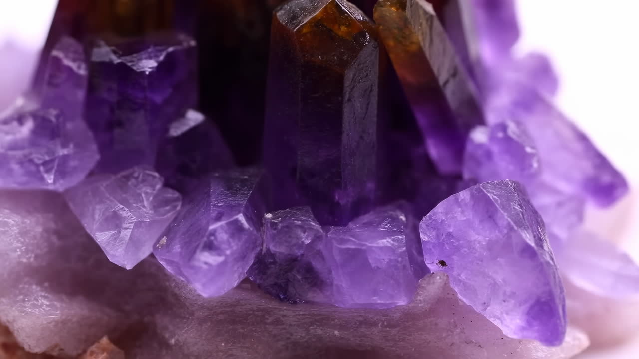 Close-up de agrupamento de cristais de ametista roxa, revelando facetas violeta profundo e pontas translúcidas em uma base de geodo bruto.