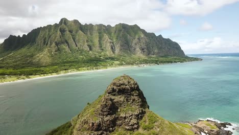 drone shot approaching chinaman's hat island with kualoa ranch and kualoa mountain range in the background