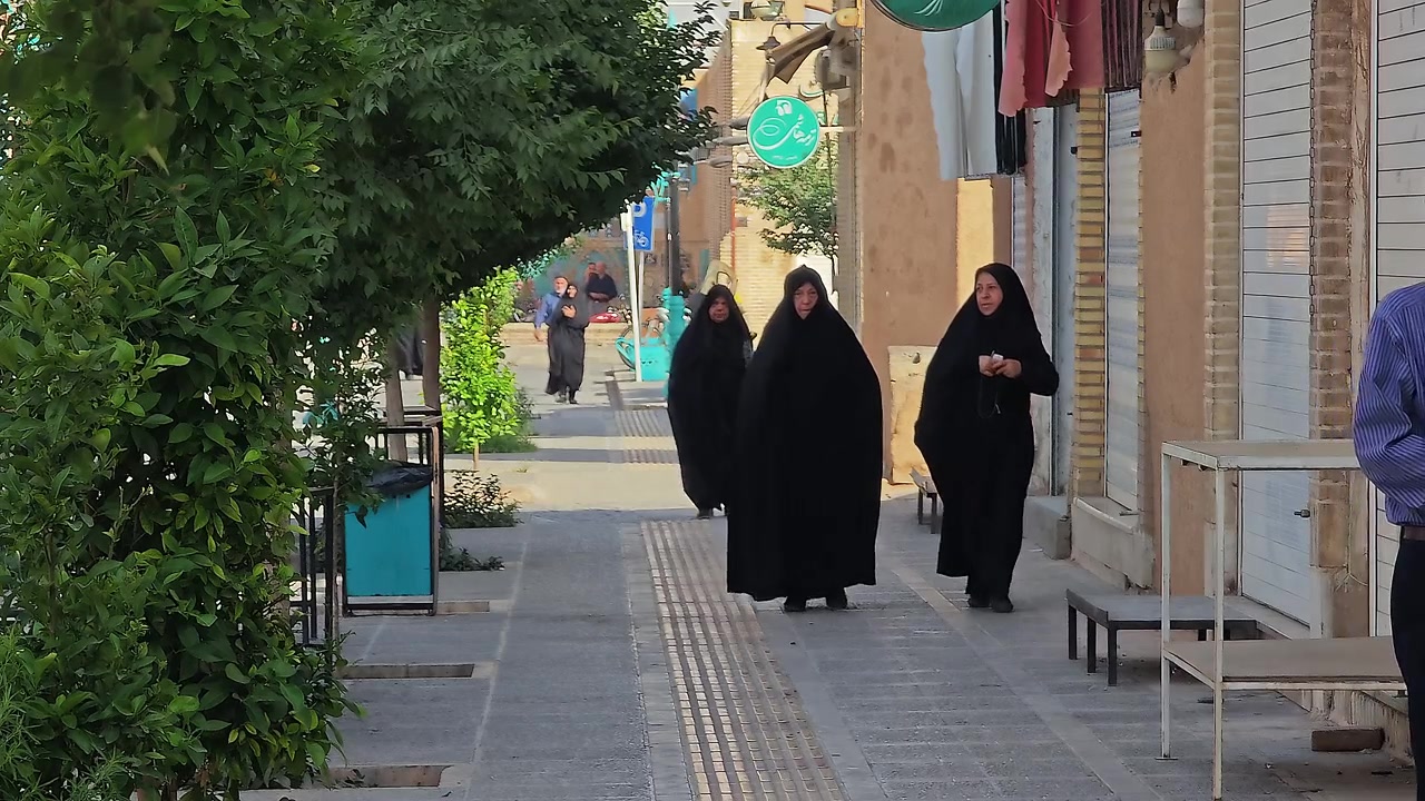 Kvinder i chadorer, der går langs et fortov i Iran