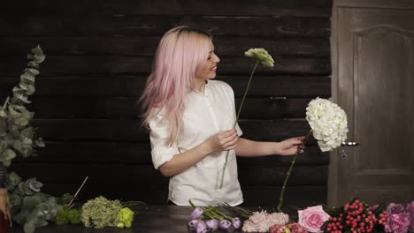 Happy,-beautiful-girl-florist-in-a-white-shirt-enthusiastically-chooses-flowers-for-a-composition-from-a-wide-assortment-of-flowers.-Slow-motion