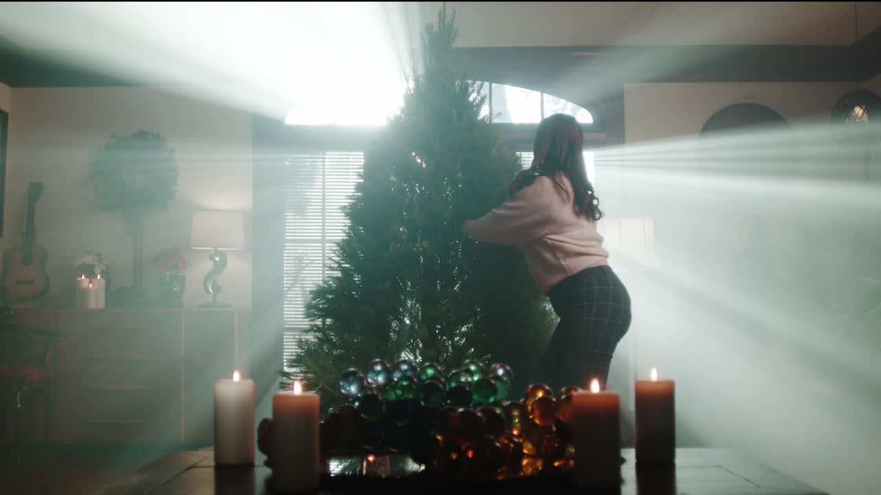 Woman decorating a Christmas tree in a sunlit room