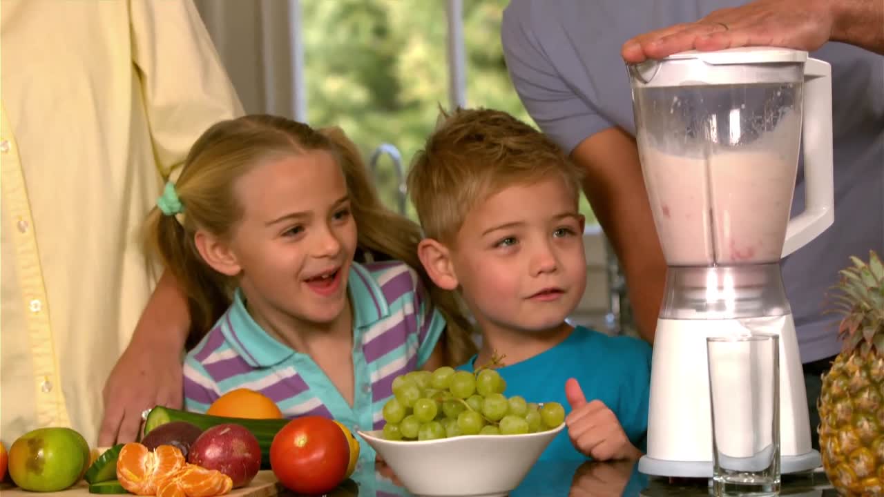 Famiglia sorridente che prepara un frullato in cucina
