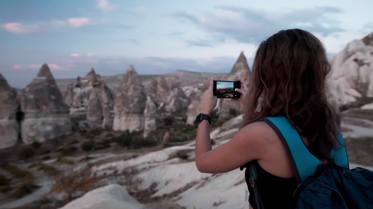 Mulher Filmando Formações Rochosas Únicas com Smartphone ao Entardecer