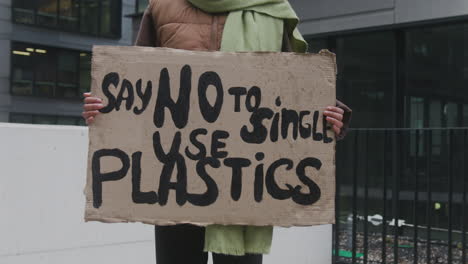 close up of an unrecognizable climate activist holding a cardboard placard against the single use plastics