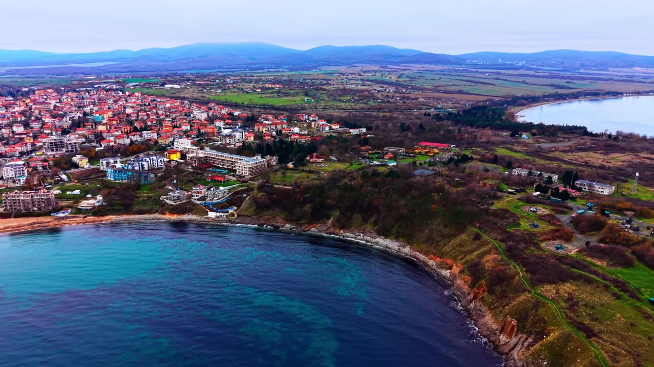 Rannikkokaupungin siluetti mereltä nähtynä, Bulgaria. Ilmakuva rinteessä olevista rakennuksista, metsästä ja rantaviivasta, joka kohtaa turkoosin rannikkoveden