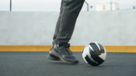 feet of athlete skillfully maneuvering soccer ball during training session on outdoor sports court, precision, background features concrete wall and yellow edge line